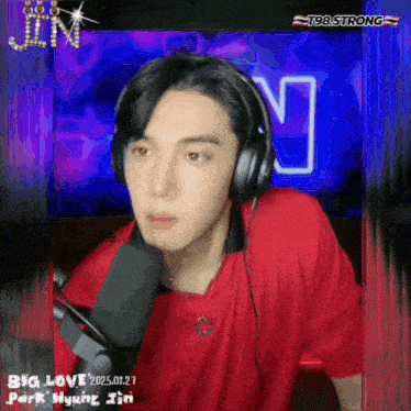 a man wearing headphones and a red shirt is sitting in front of a microphone with the words big love behind him