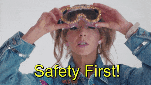a woman wearing a denim jacket is holding a pair of goggles and says " safety first "