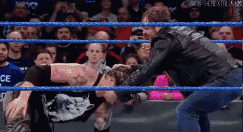 two men are wrestling in a wrestling ring in front of a crowd of people .