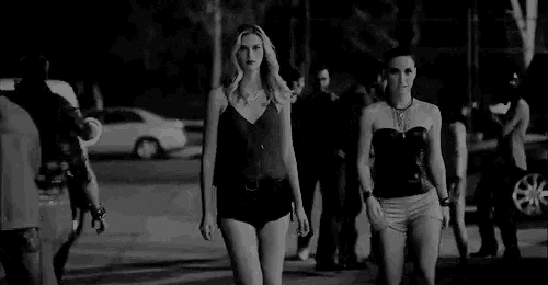 two women are walking down the street at night .