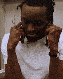 a man with dreadlocks is wearing a white shirt and a black watch
