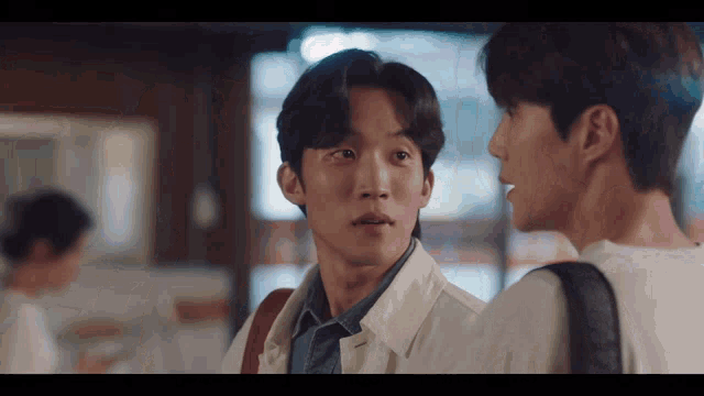 two men are standing next to each other and talking to each other