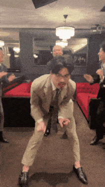 a man in a suit is dancing in a room with other people