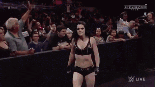 a woman in a black bra is standing in front of a crowd and screaming .
