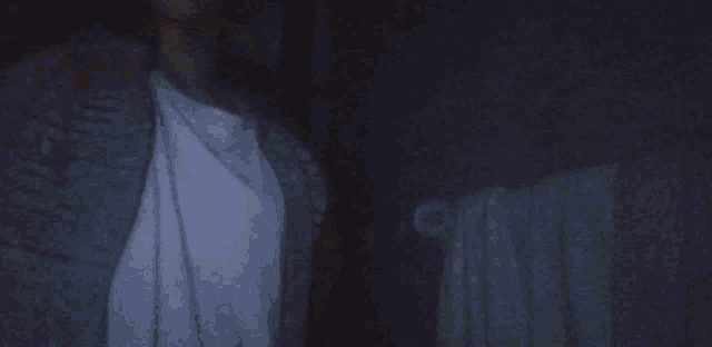 a person in a white shirt is standing in a dark room .