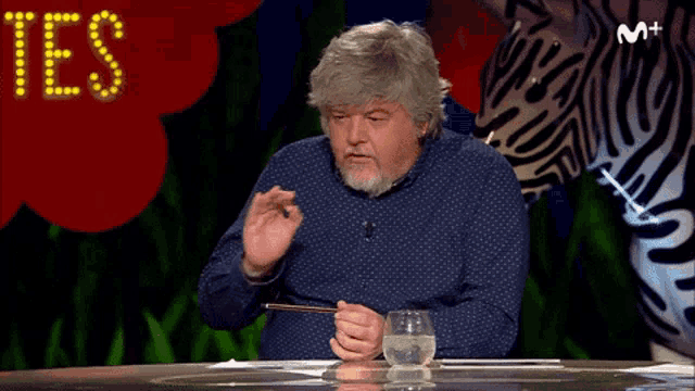 a man sits at a table in front of a sign that says ' yes ' on it