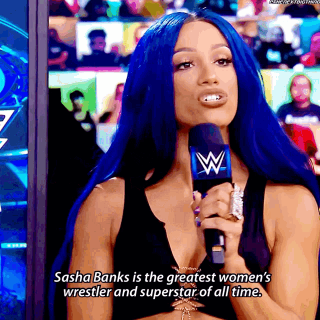 a woman with blue hair is holding a microphone and says sasha banks is the greatest women 's wrestler of all time