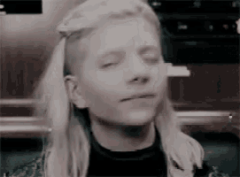 a woman with blonde hair and a shaved head is making a funny face with her eyes closed .