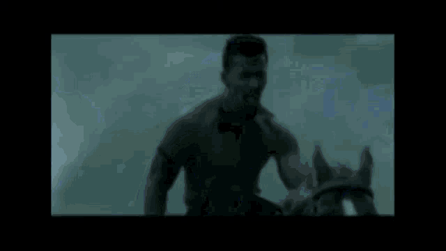 a blurry picture of a man standing in a dark room holding a sword .