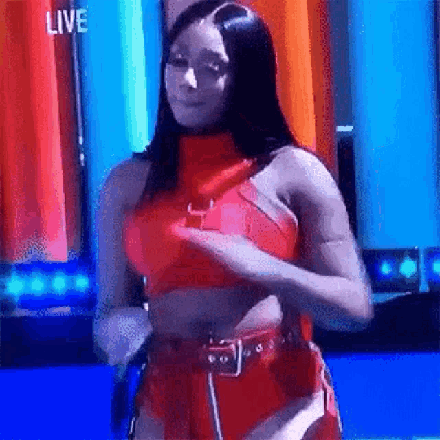 a woman in a red crop top and shorts is standing in front of a blue curtain .