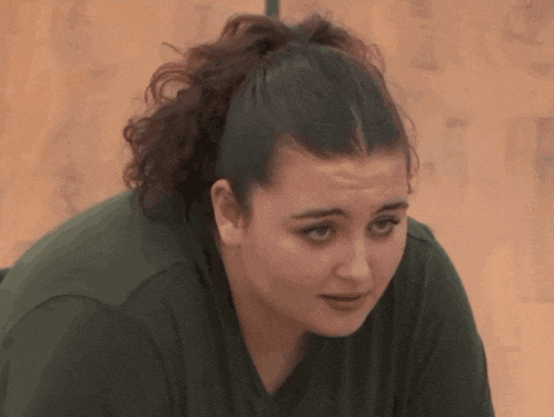 a woman with a ponytail and a green shirt is looking down