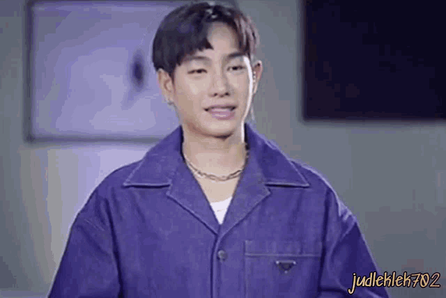 a young man wearing a blue jacket and a chain around his neck .