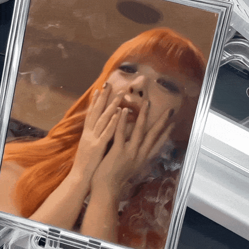 a woman with long red hair looks at herself in a mirror