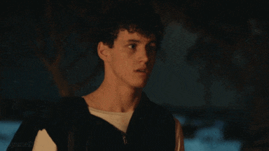 a young man with curly hair is wearing a black jacket and white shirt