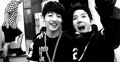two young men are standing next to each other and smiling .
