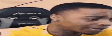 a man in a yellow shirt is sitting in front of a chair and making a funny face .