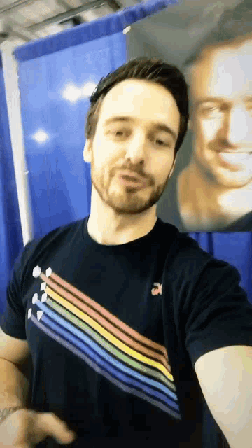 a man taking a selfie in front of a painting of another man
