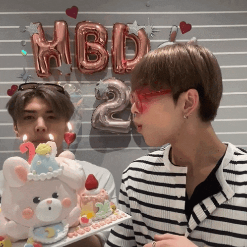 a man blowing out candles on a cake that says 2 on it