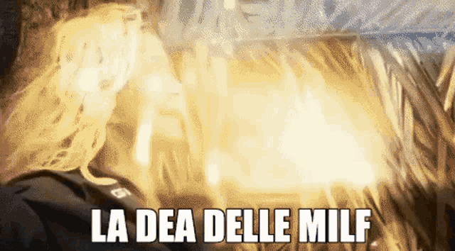 a woman is standing in front of a fire and the words la dea delle milf are on the bottom