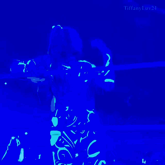 a woman in a glow in the dark outfit is standing in a ring with the name tiffany luv24 on the bottom