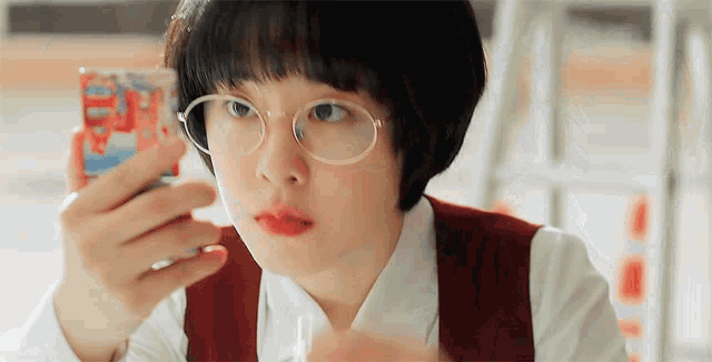 a young girl wearing glasses is looking at her phone