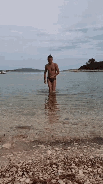 a man in swim trunks stands in the water