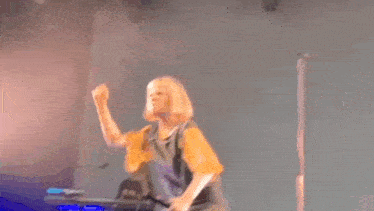 a woman is singing into a microphone on a stage while dancing .