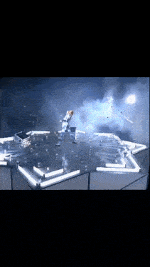 a person in a white suit is standing on a stage with a lot of lights on it