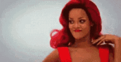 a woman with red hair is wearing a red dress and making a funny face .