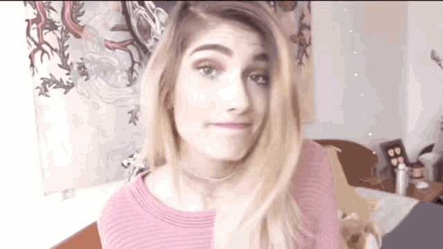 a woman in a pink sweater is making a funny face .