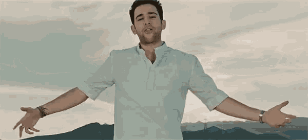 a man is standing with his arms outstretched in front of mountains