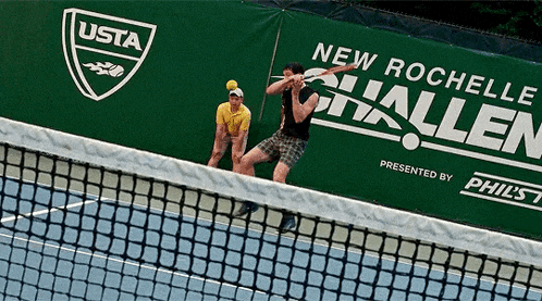 two men are playing tennis in front of a banner that says " new rochelle hallen "