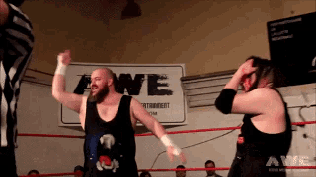 two men in a wrestling ring with a sign that says awe