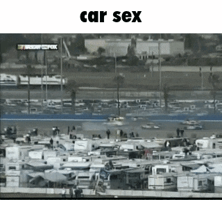 a bunch of rvs are parked in a lot in front of a race track .