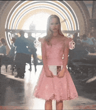 a woman in a pink dress is holding a book that says ' a ' on it