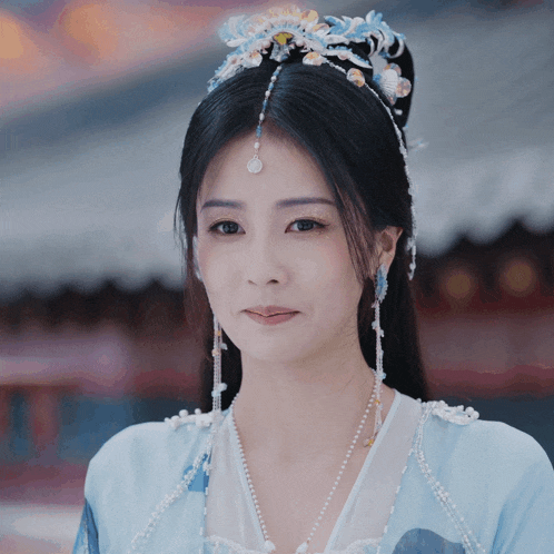 a woman wearing a blue and white dress with pearls and a tiara