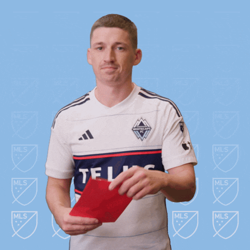 a man in a white adidas shirt holds a red card in his hand