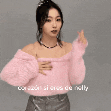 a woman in a pink off the shoulder sweater with the words corazon si eres de nelly on the bottom