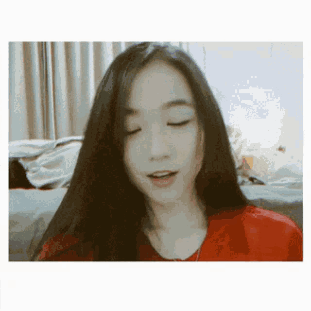 a woman with long black hair is wearing a red top
