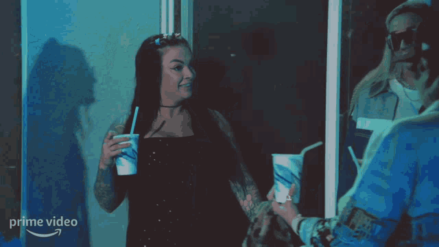a woman holding a cup with a straw in front of a prime video sign