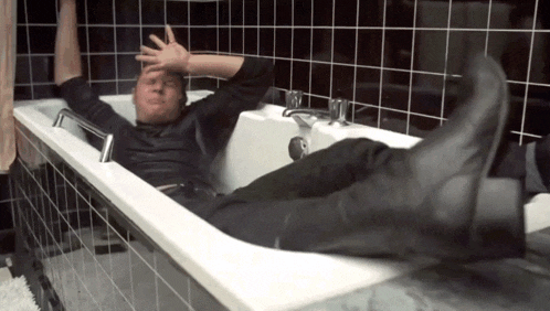 a man is laying in a bathtub with his legs up