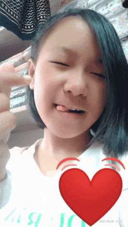 a girl is making a funny face with a red heart behind her