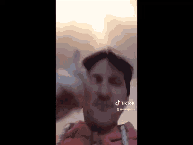 a man is making a funny face and giving a thumbs up in a tik tok video .