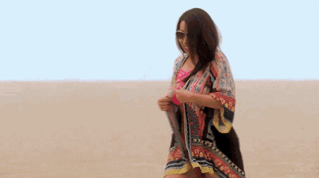 a woman in a bikini is walking on the beach .