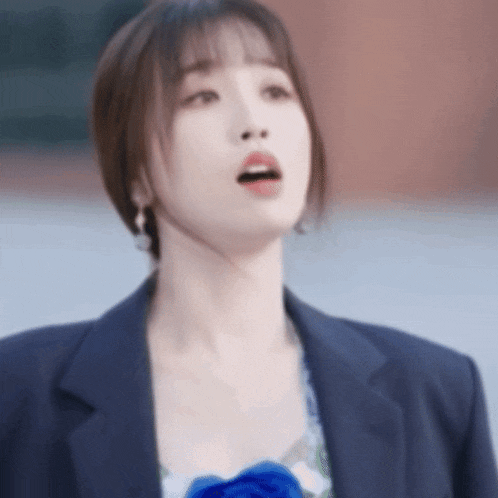 a woman wearing a blue jacket and a blue flower on her chest