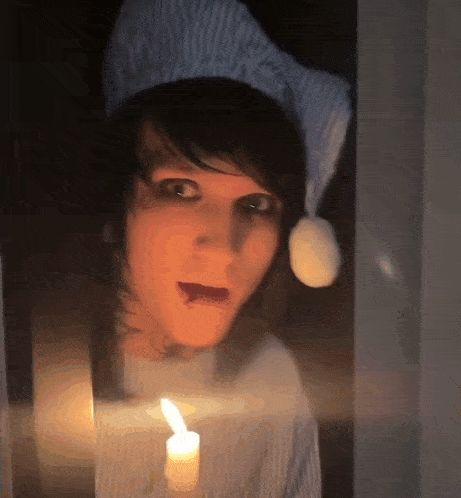 a person wearing a hat and holding a candle