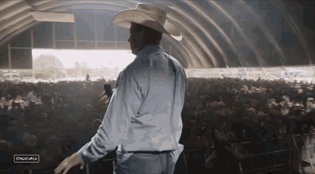 a man in a cowboy hat is standing in front of a crowd of people with the words stagelam on the bottom left