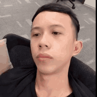a man in a black shirt is sitting in a chair and looking at the camera
