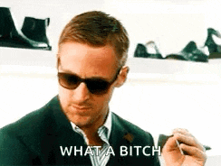 a man wearing sunglasses and a suit is smoking a cigarette .