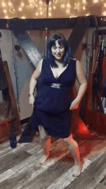 a woman in a blue dress is dancing barefoot in a room .